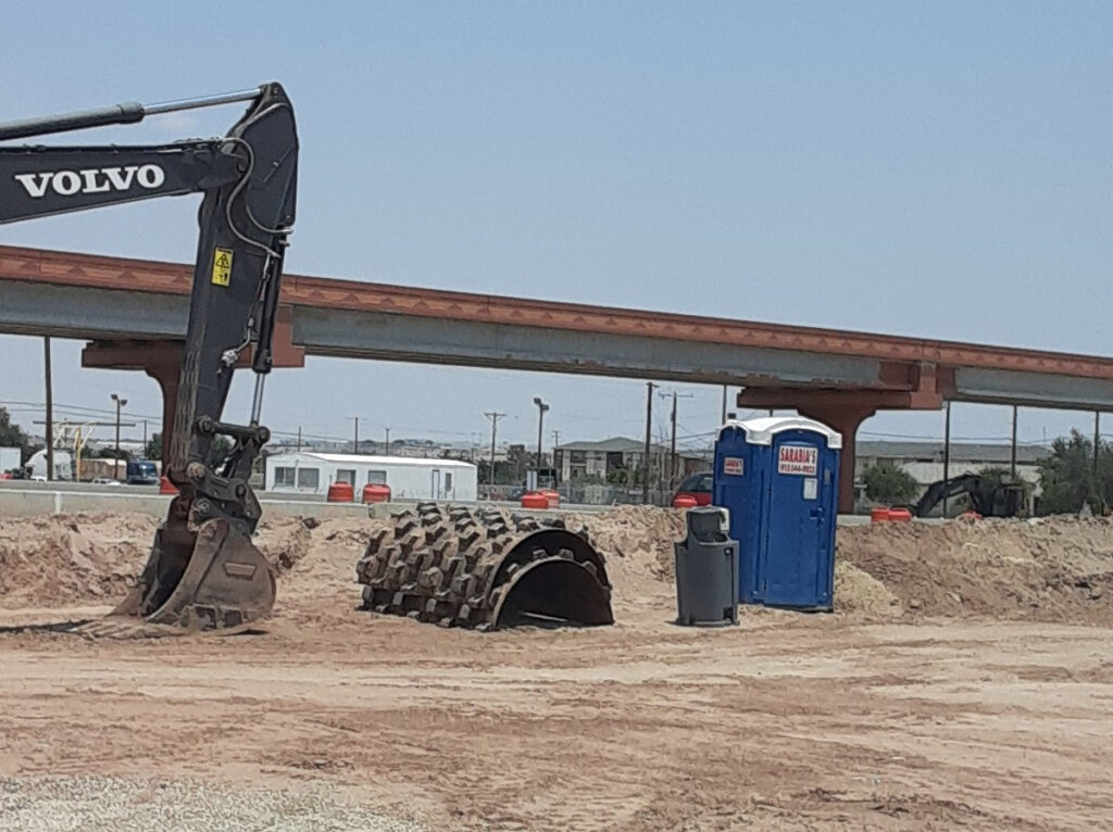 A blue porta potty and portable hand washing station at an El Paso construction site.