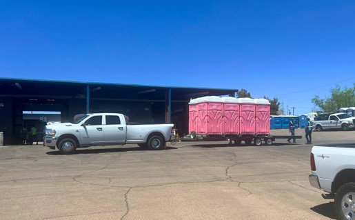 A truck pulling a trailer full of pink portable toilet rentals in El Paso.