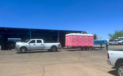 A truck pulling a trailer full of pink portable toilet rentals in El Paso.