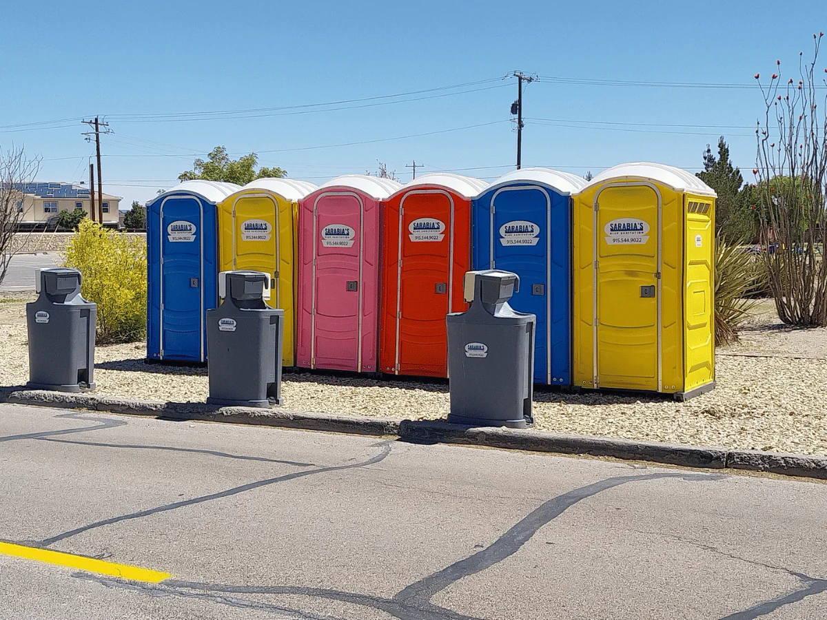 Variety of different color portable toilets with handwashing stations.